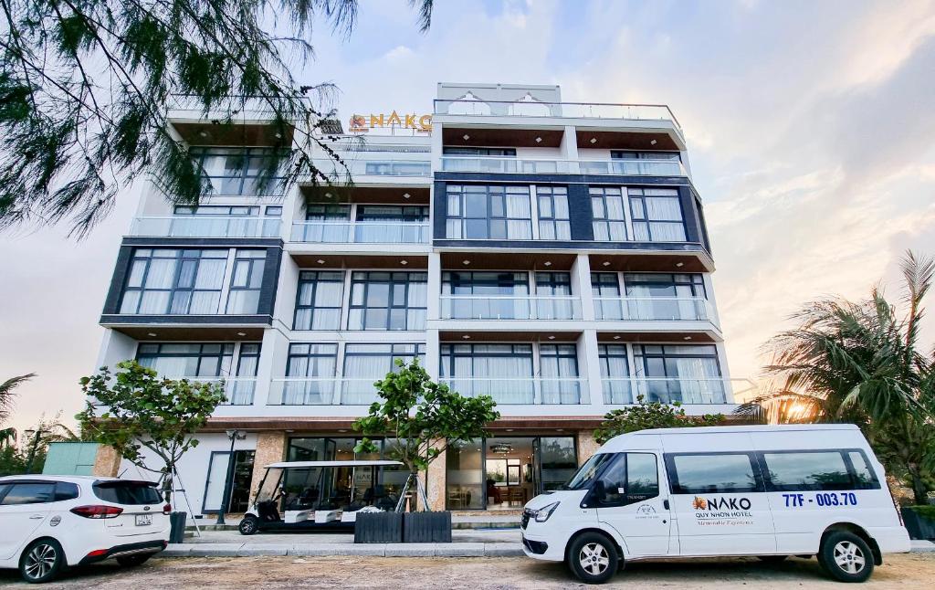 归仁NAKO QUY NHON HOTEL的两辆白色货车停在大楼前