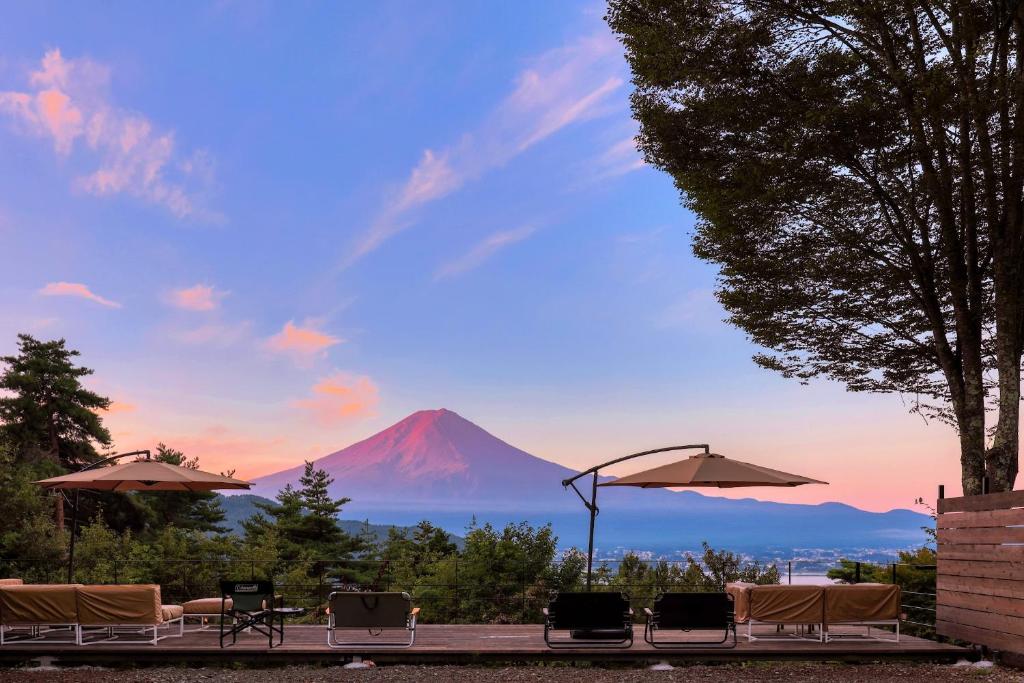 富士河口湖Retreat Camp Mahoroba的享有带椅子和遮阳伞的山景