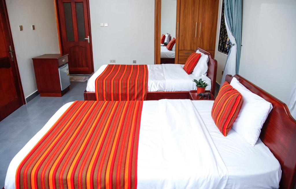 坎帕拉Fred and Winnie BnB的酒店客房,配有两张红色和橙色条纹床单