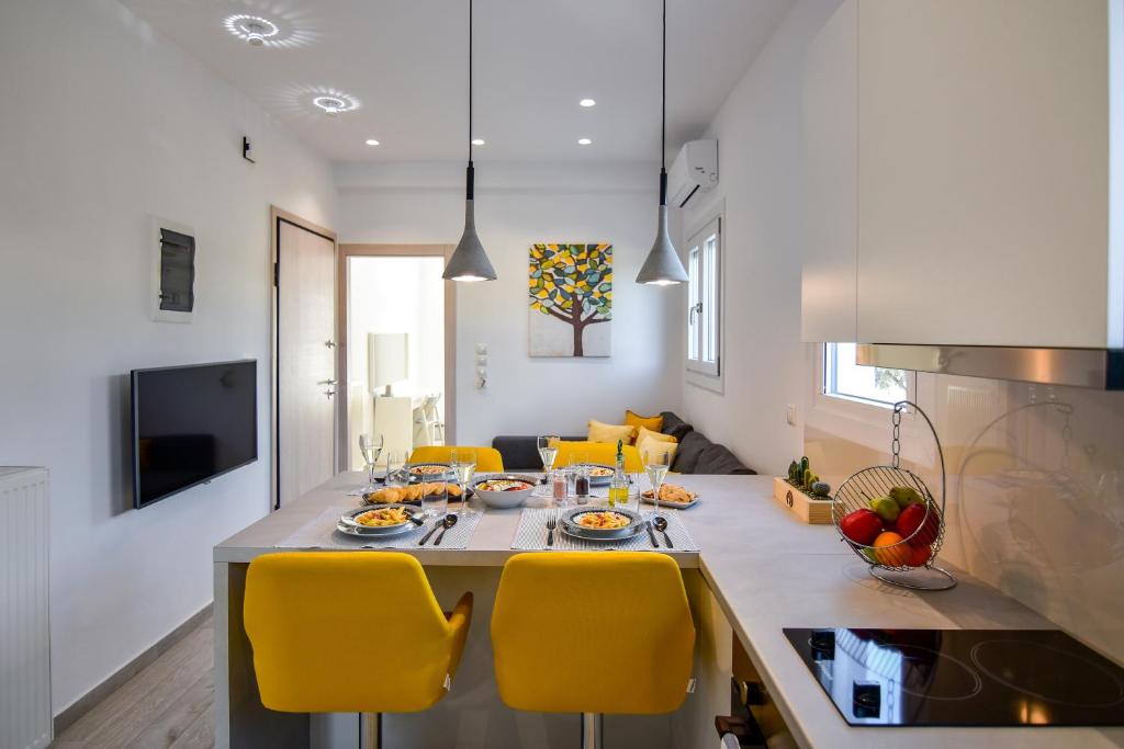 阿达玛斯White Rock Milos Suites的厨房以及带桌子和黄色椅子的用餐室。