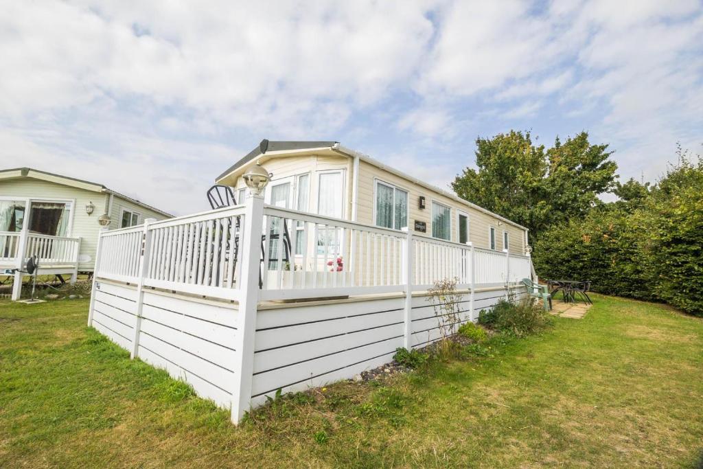 大雅茅斯Beautiful 8 Berth Caravan At Cherry Tree Holiday Park In Norfolk Ref 70803c的院子中白色围栏的房子