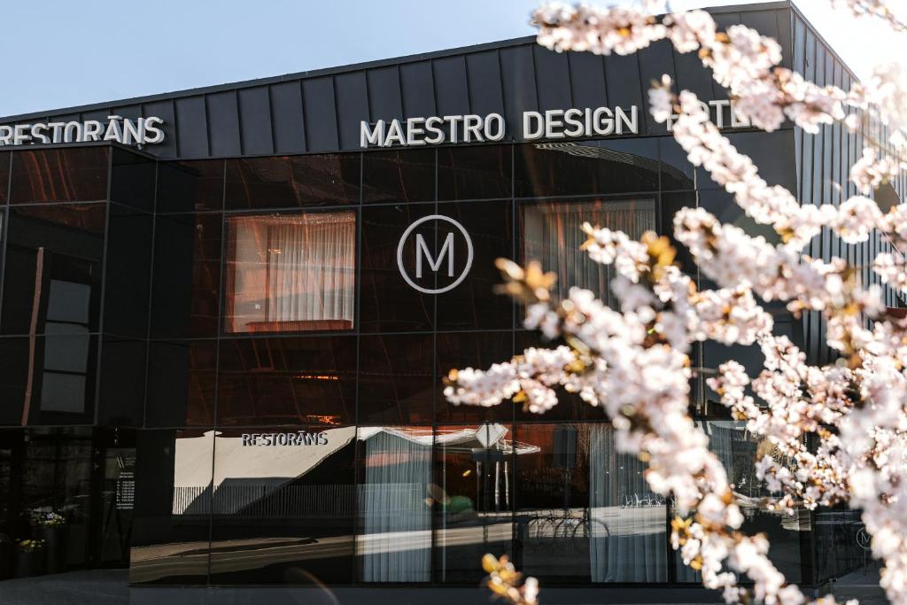 利耶帕亚Maestro Design Hotel的一座马苏埃多设计建筑,前面有一棵树