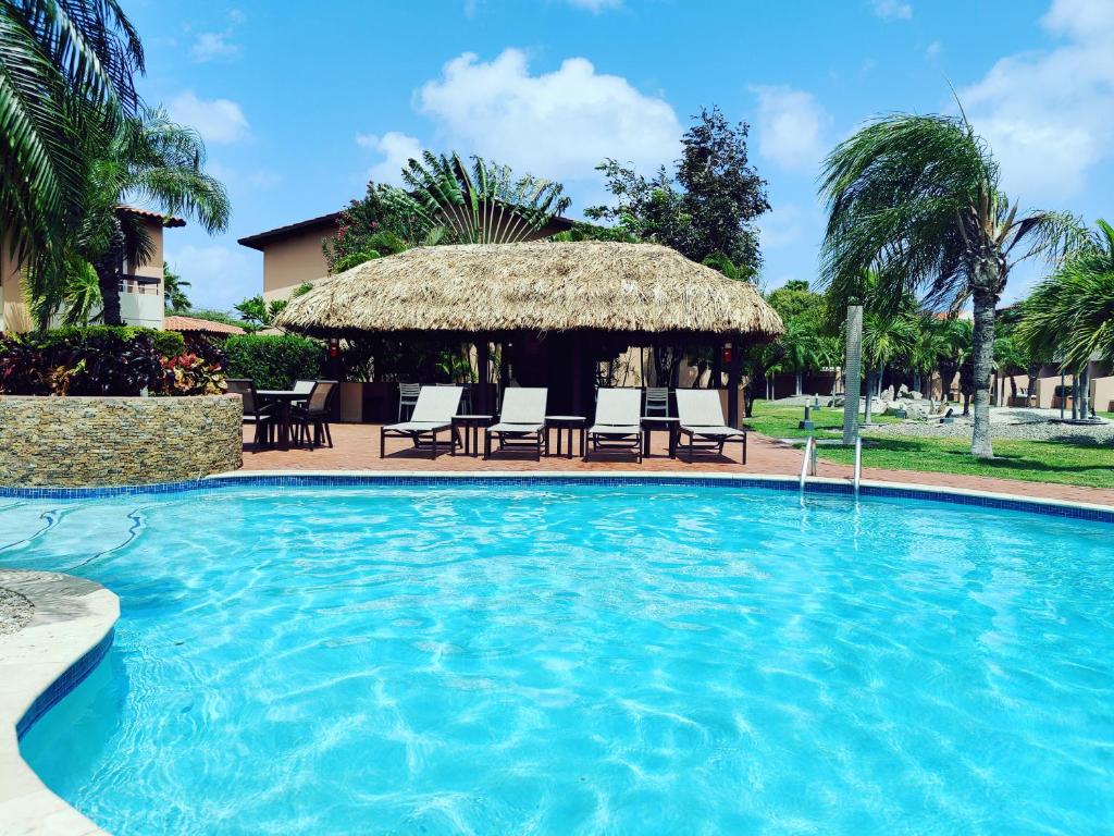 棕榈滩Luxury two-bedroom townhome in few steps from Eagle Beach的一个带椅子的游泳池和一个凉亭