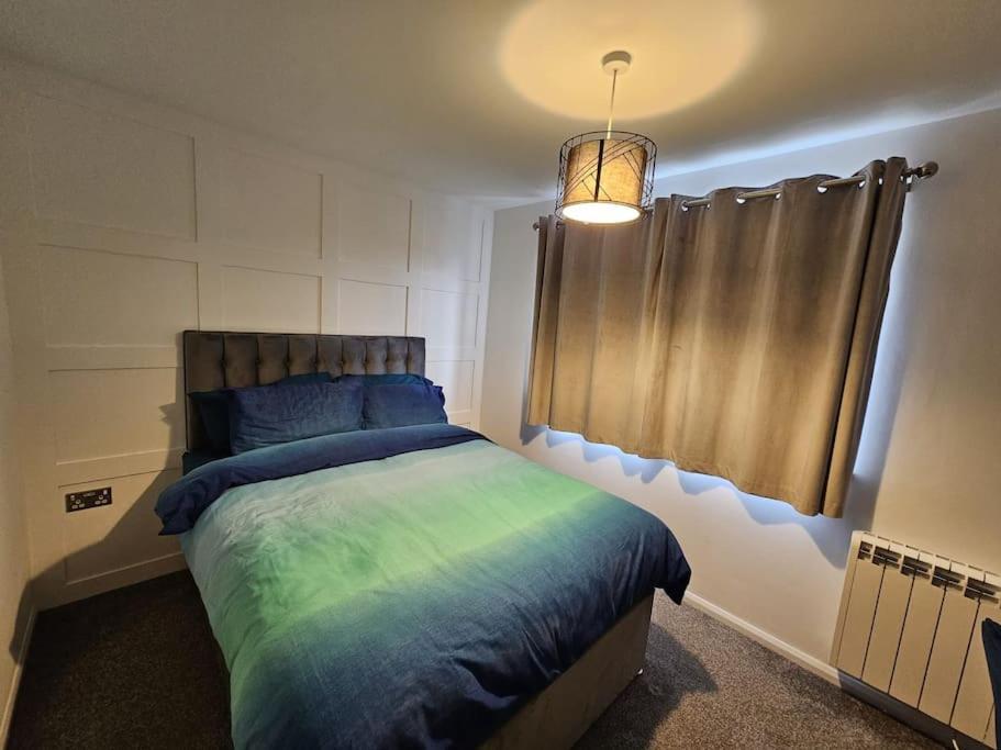 史云顿Entire Spacious Modern One Bedroom House的一间卧室配有一张蓝色和绿色床单。