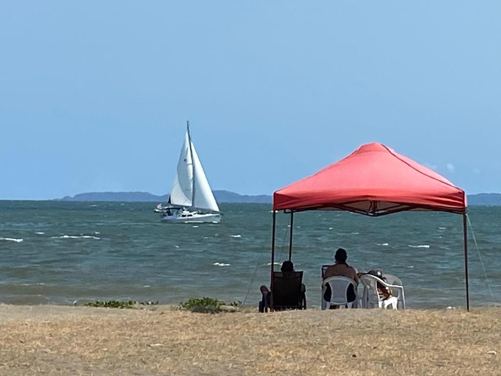 蓬塔雷纳斯Frente al mar loft的坐在海滩上红伞下椅子上的男人