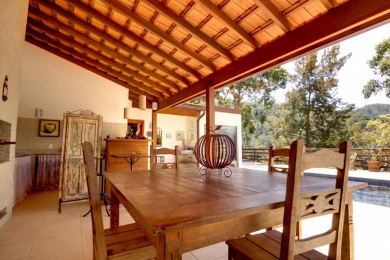 伊泰帕瓦Pousada Alto Itaipava的一间带木桌和大窗户的用餐室