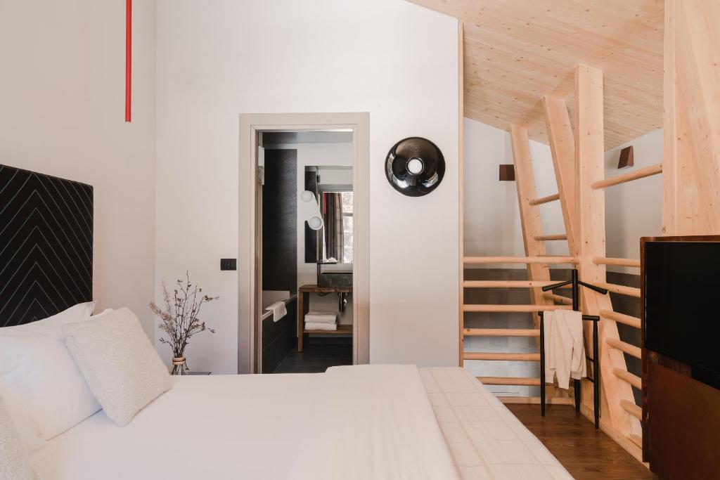尚波吕克Aethos Monterosa的卧室设有白色的床和木制楼梯。