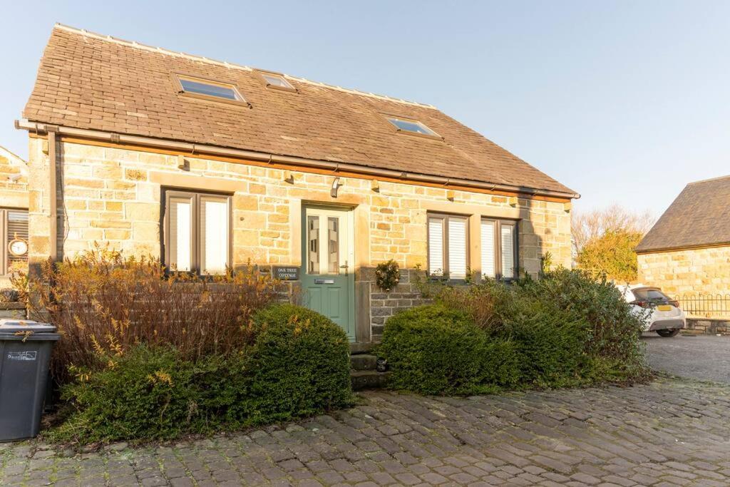 伯恩利Oak Tree Cottage - Pendle - Forest of Bowland的街上有一扇绿门的砖房