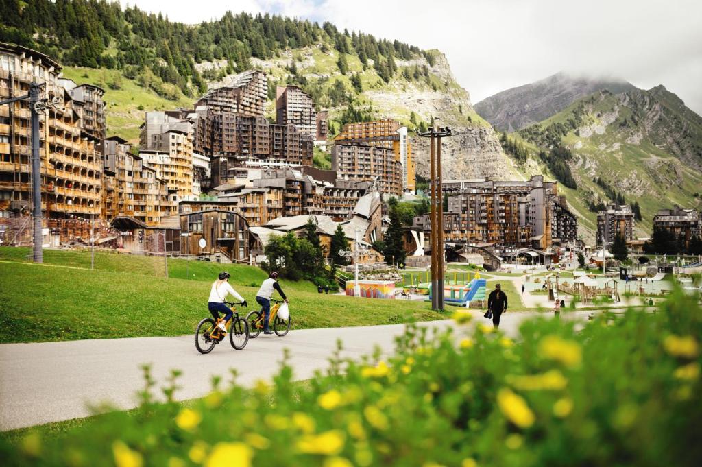 阿沃里亚兹Belambra Clubs Avoriaz - Les Cimes du Soleil的两个人骑着自行车沿着城市的街道骑着