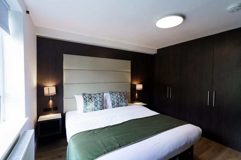 伦敦Penywern Apartment Earls Court的一间卧室配有一张大床和深色木橱柜