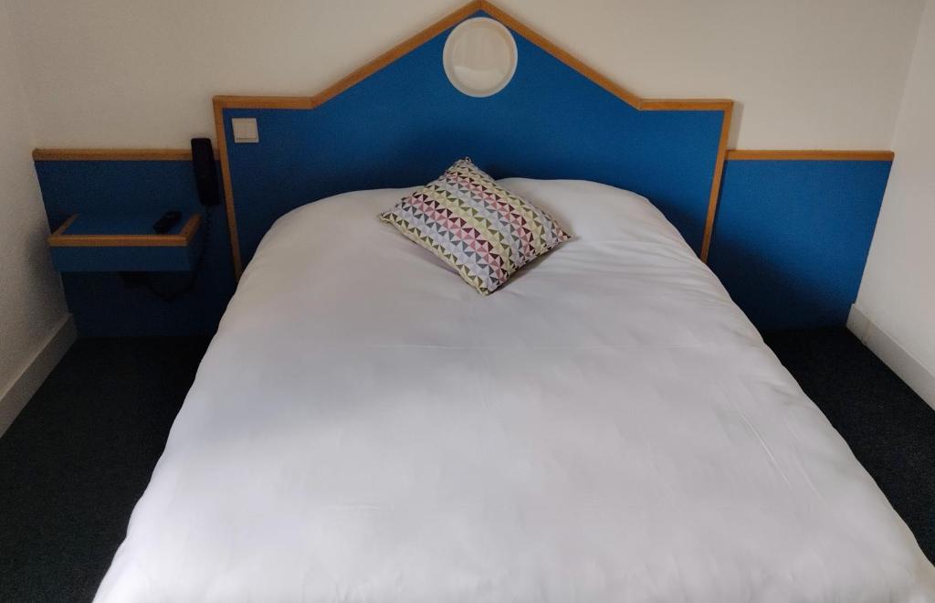 萨尔特河畔萨布雷initial by balladins Sable sur Sarthe的一张带枕头的蓝色床头板的床