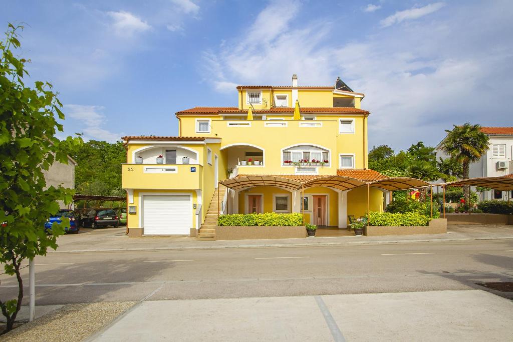 奈维斯Apartmani Justić的前面有一个白色车库的黄色房子