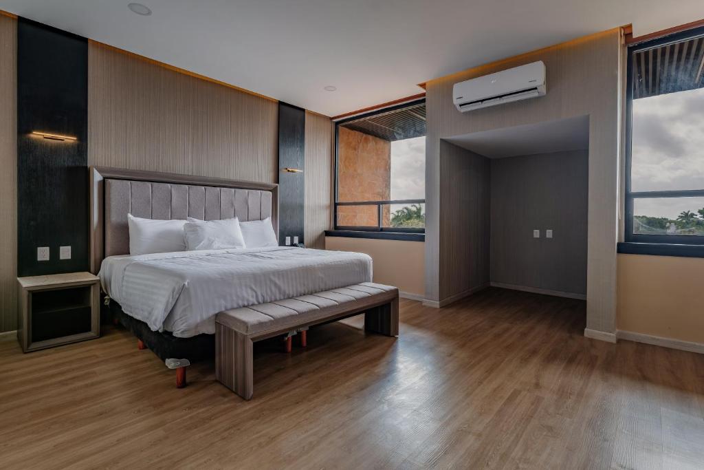 梅里达Hotel Kavia Premium - Paseo Montejo的一间卧室设有一张大床和两个窗户。