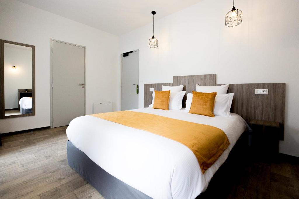朗戈涅Grand Hôtel 1899的卧室配有带橙色枕头的大型白色床