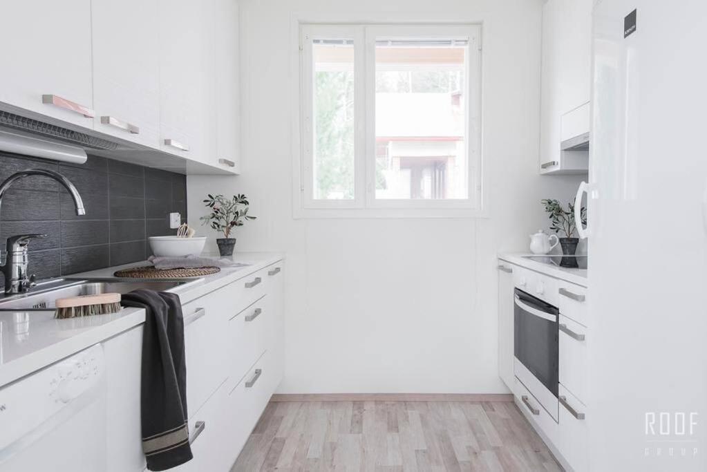 赫尔辛基100m2 moderni paritalo omalla pihalla Helsingissa的白色的厨房配有白色橱柜和窗户