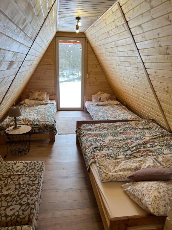 拉伊恰Domek nad Potokiem w Beskidach的阁楼卧室设有三张床和一扇窗户