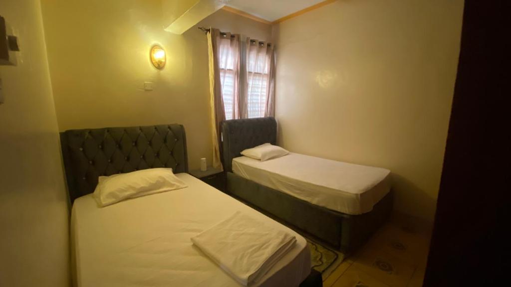 蒙巴萨Al Maaroof Appartment的小房间设有两张床和窗户