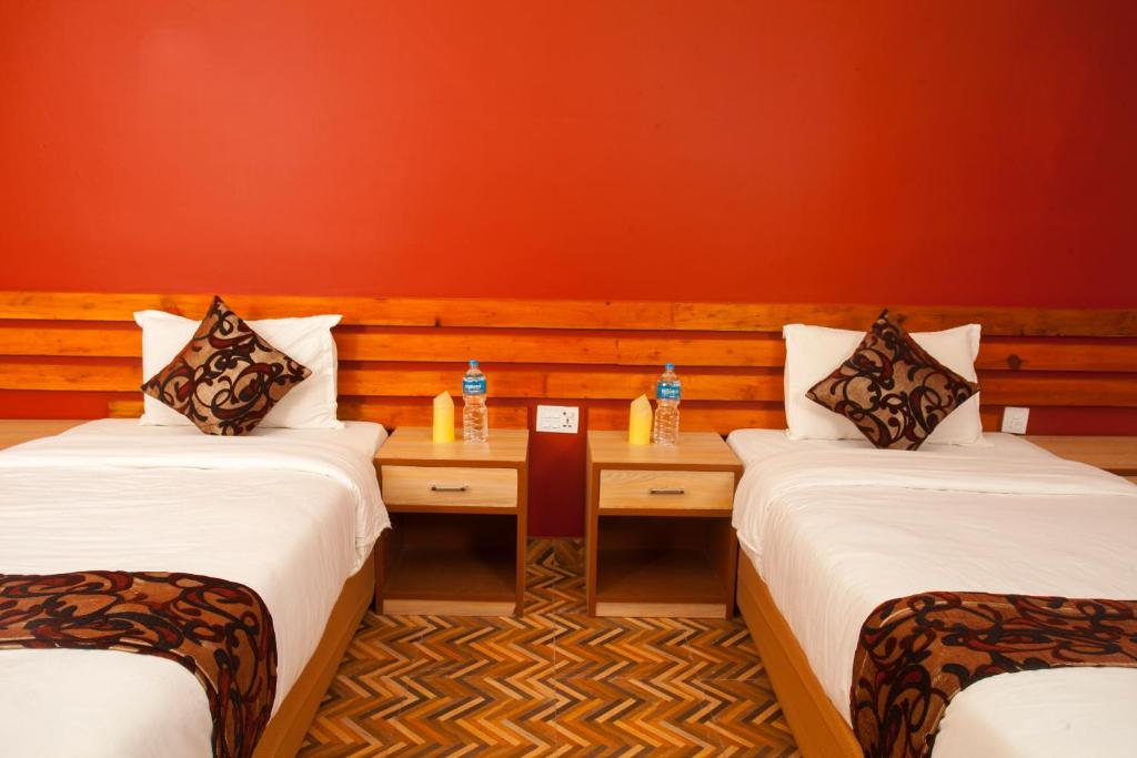奇旺Sauraha Holiday Home Riverside的一间设有两张床和一张桌子的房间,桌子上装有瓶子
