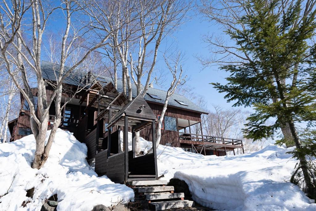 二世古Niseko HyKrots IKIGAI Village的雪地里的小木屋,有树