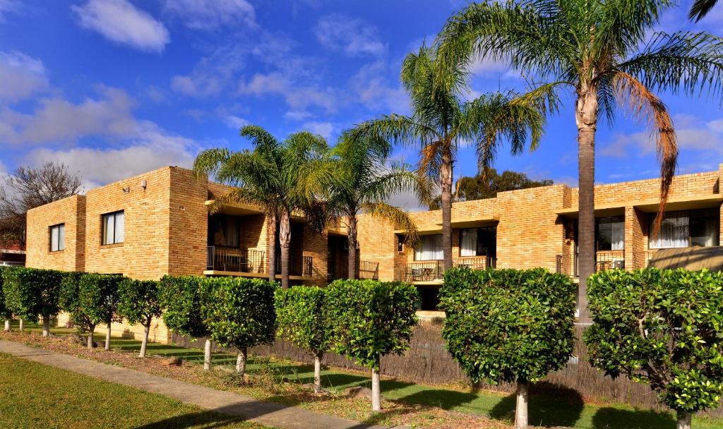 悉尼Ryde Inn的一座棕榈树和围栏的砖砌建筑