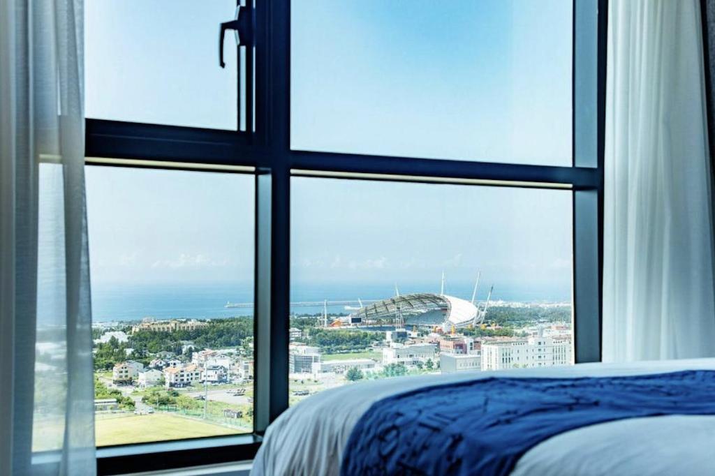 西归浦市Jeju Pureun Hotel的一间卧室,透过窗户可欣赏到体育场的景色
