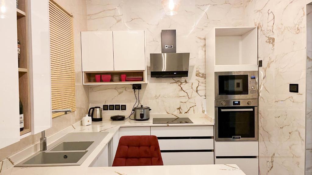 阿克拉Mariaddo homes的厨房配有白色橱柜和红色椅子