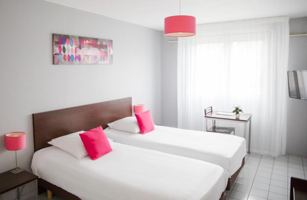 贝桑松泽尼涂德城市公寓的一间卧室配有两张白色床和红色枕头