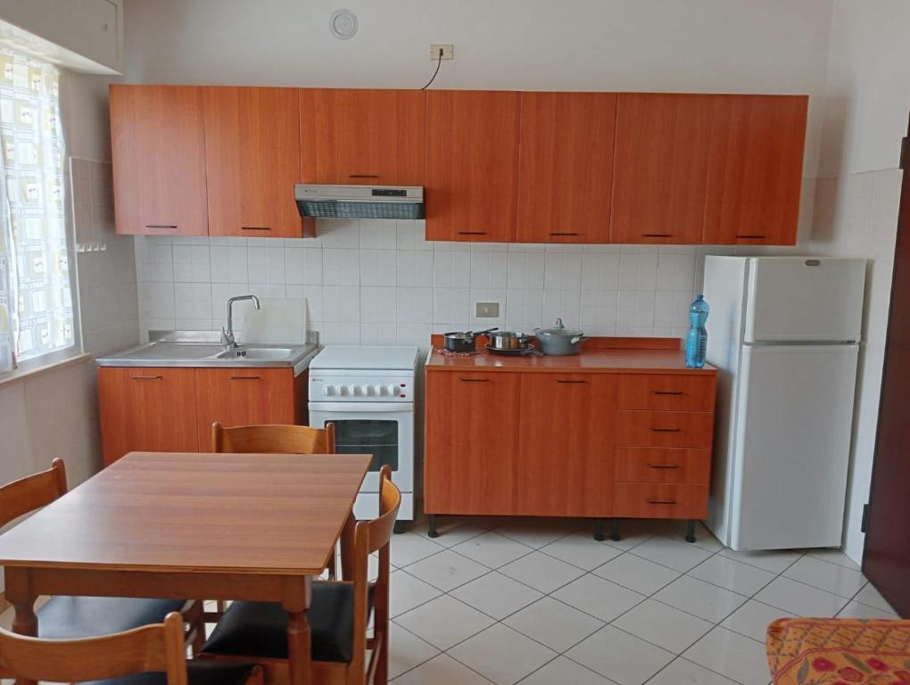 里米尼Appartamenti Carlotta的厨房配有桌子和白色冰箱。