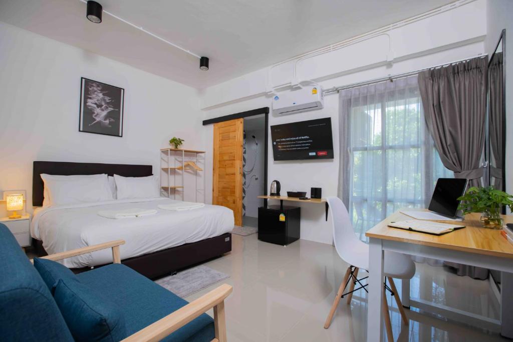 班泰Laewan Guesthouse的一间卧室配有一张床和一张带电脑的书桌
