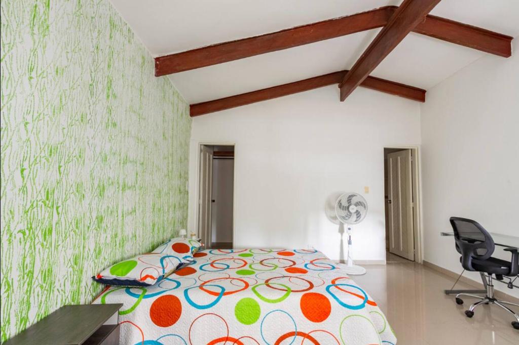 卡利La Arboleda del Rio.的一间卧室配有一张床、一张桌子和风扇