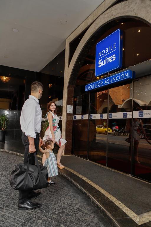 亚松森Nobile Suites Excelsior Asuncion的站在建筑物前的男女和儿童
