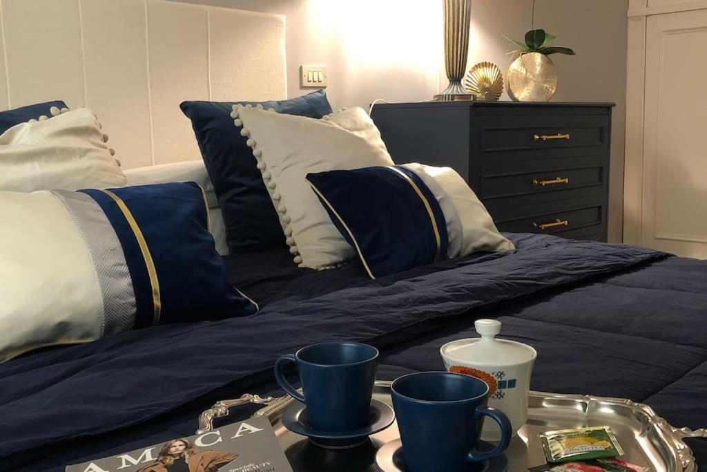 普拉托Rosymarty Apartment-vicino Firenze的一张带蓝色和白色枕头的床和一个带杯子的托盘