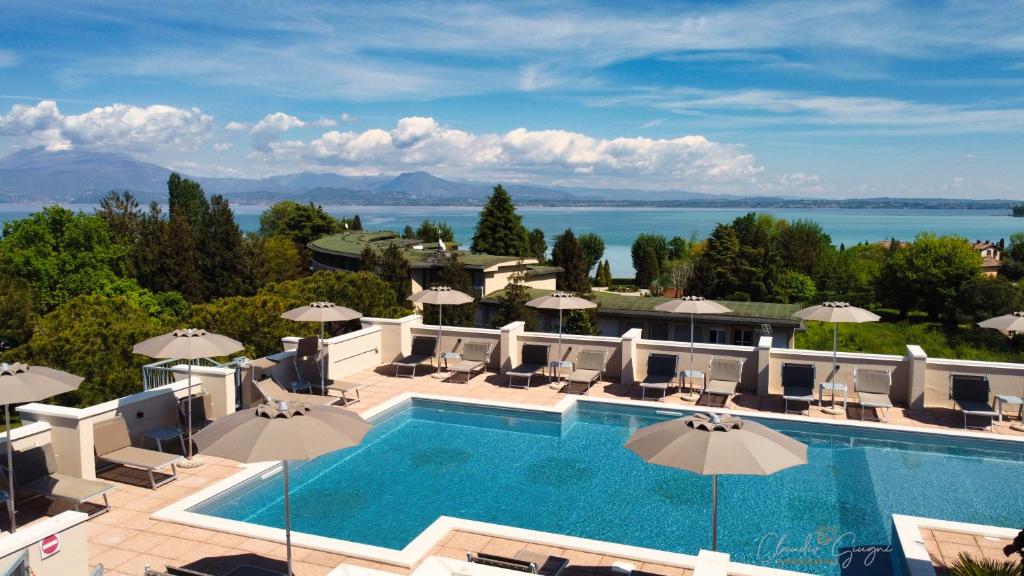 西尔米奥奈Hotel Alfieri的一个带遮阳伞和海洋的大型游泳池