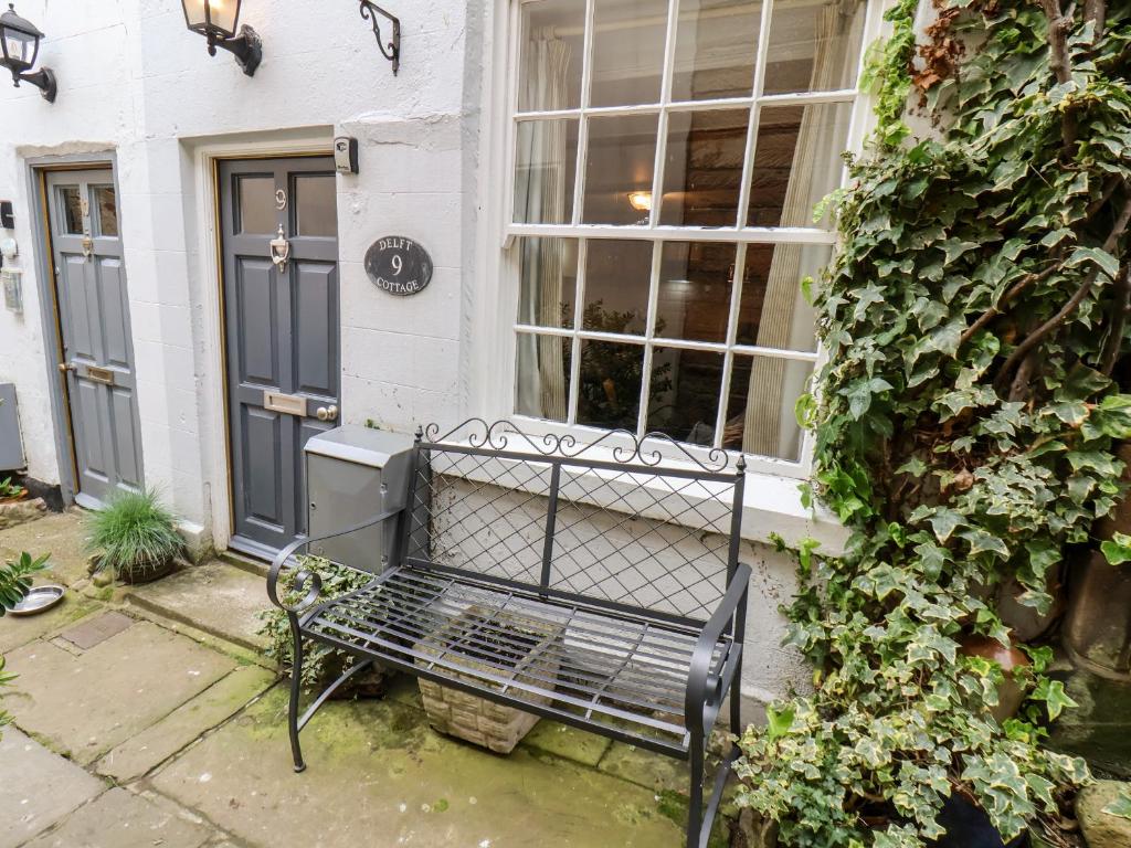 罗宾胡兹贝Delft Cottage的坐在房子外的黑长凳