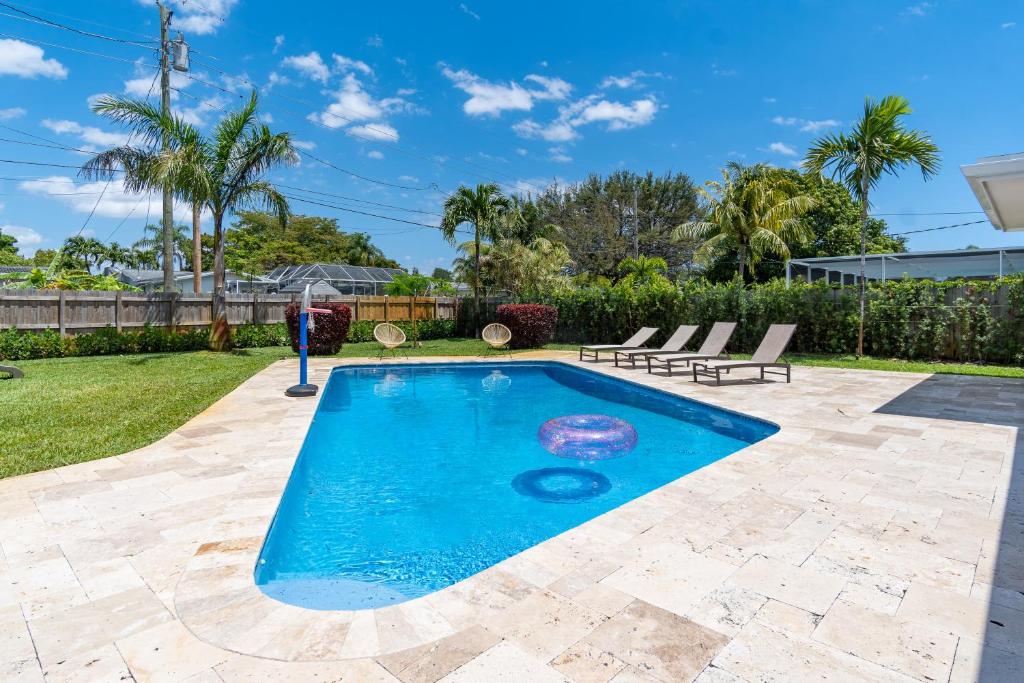 好莱坞Hollywood Paradise Luxury 4BR 3BA Home and Outdoor Fun with Heated Pool的一个带2把躺椅的庭院内的游泳池