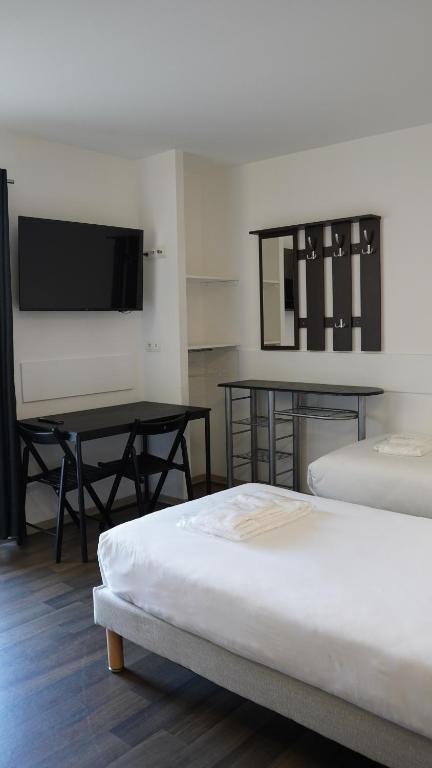 里摩日Apparts Confort 87的客房设有两张床、一张桌子和一台电视机。