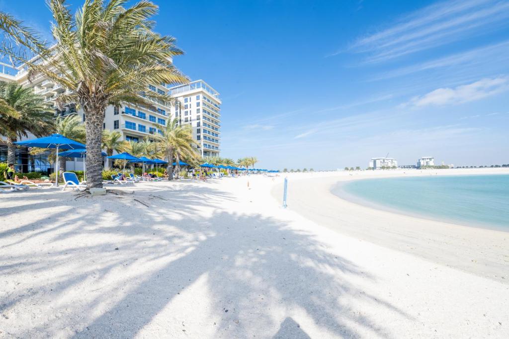 拉斯阿尔卡麦Luxury 1BR Beachfront Apartment Marjan Island的棕榈树和海洋的白色沙滩