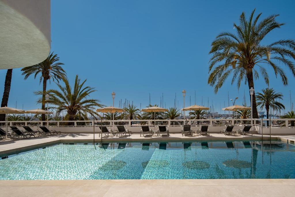 马略卡岛帕尔马Hotel Palma Bellver , Affiliated by Meliá的一个带椅子和遮阳伞的游泳池以及棕榈树