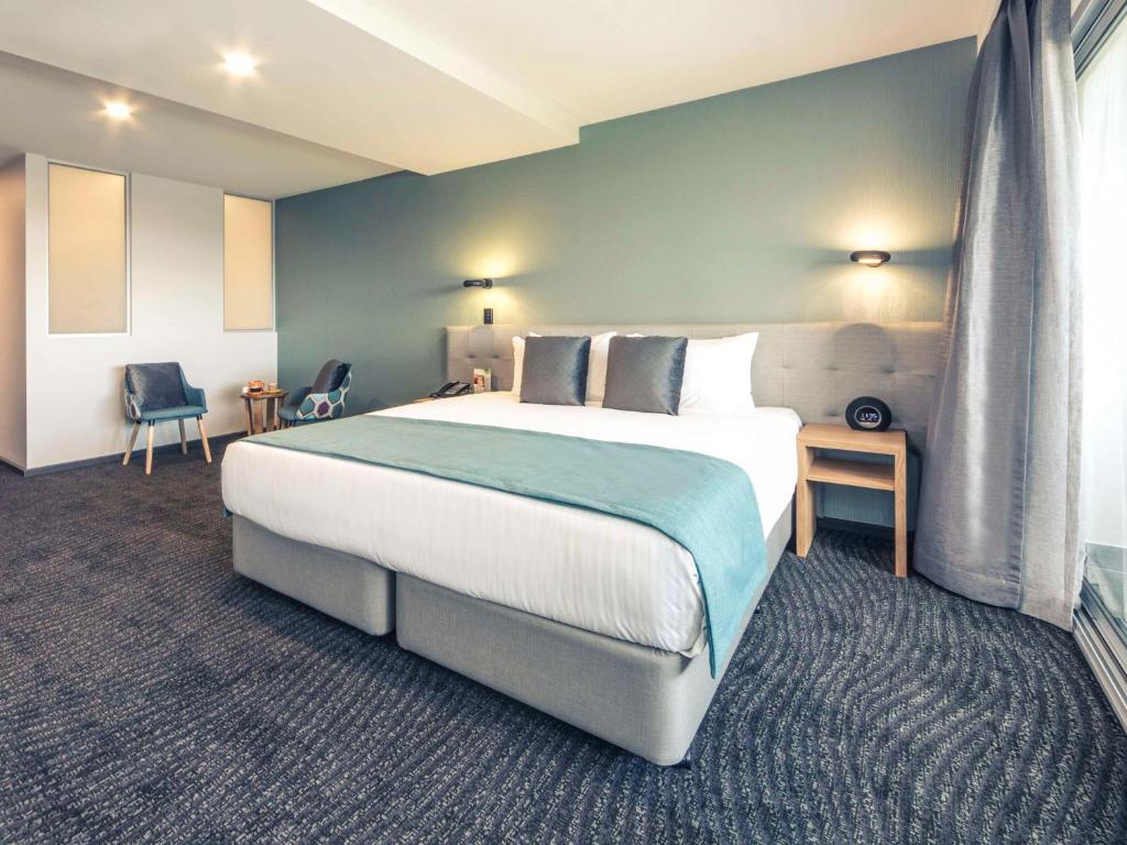 卡洛琳温泉墨尔本加罗林温泉美居酒店的一间卧室设有一张大床和蓝色的墙壁