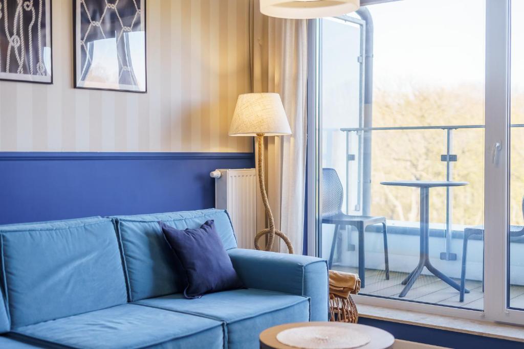 科沃布热格Apartamenty Fenomen - Horizon, Nadmorskie Tarasy FREE PARKING, SWIMMING POOL, SAUNA AND OTHER!的客厅配有蓝色的沙发和桌子