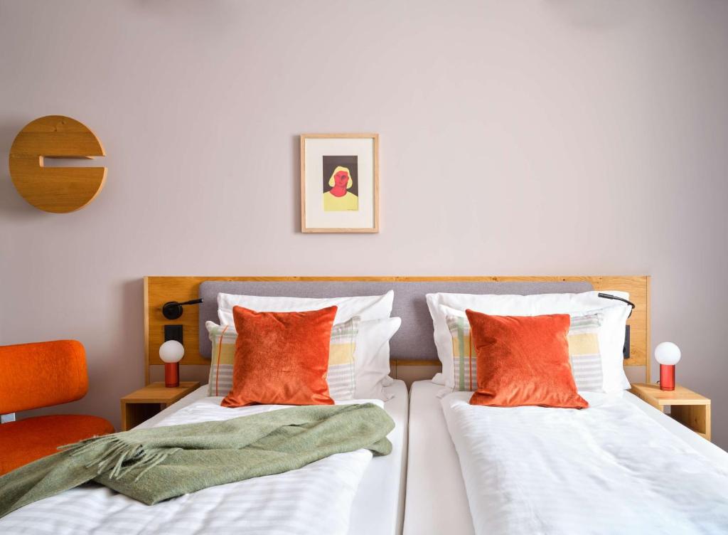 慕尼黑Flemings Hotel München-Schwabing的两张带橙色和白色枕头的床