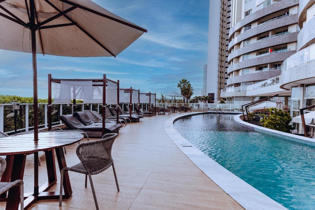 纳塔尔金色郁金香纳塔尔蓬内格拉酒店的一座带桌椅的游泳池位于酒店大楼旁