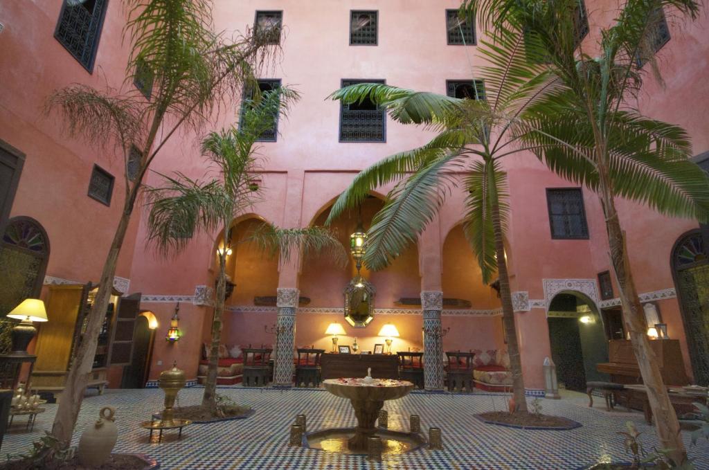 非斯达尔安妮巴旅馆的一座种有棕榈树的庭院和一座粉红色的建筑