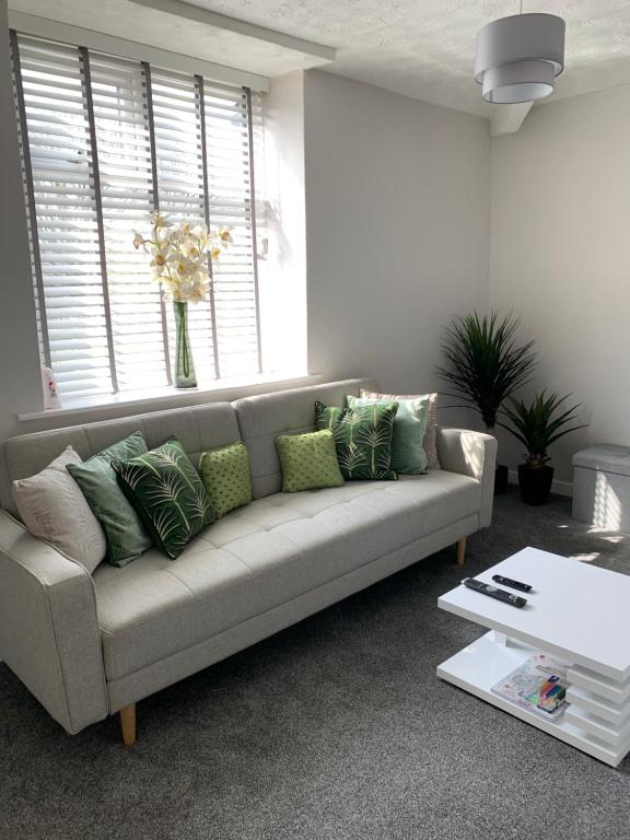 FarnworthThe Greens Apartment的客厅配有带绿色枕头的灰色沙发