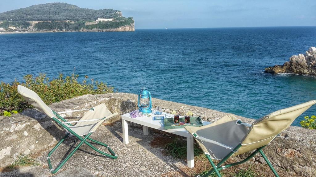 加埃塔Gaeta Villino Isabella的一张桌子和两把椅子坐在水边的墙上
