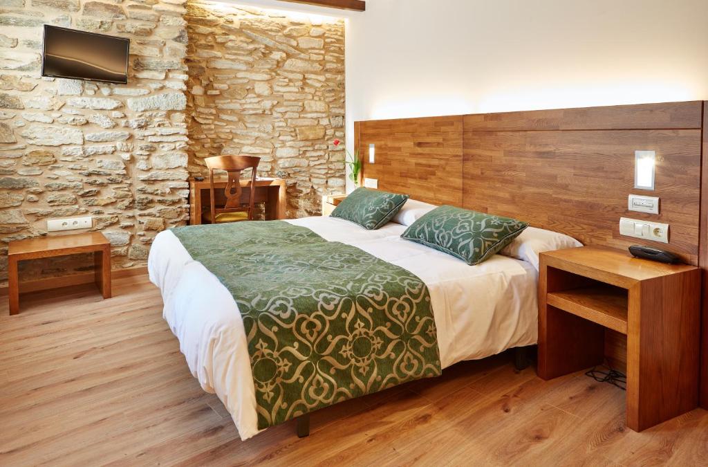 圣地亚哥－德孔波斯特拉Mapoula PR Boutique的一间卧室设有一张大床和石墙