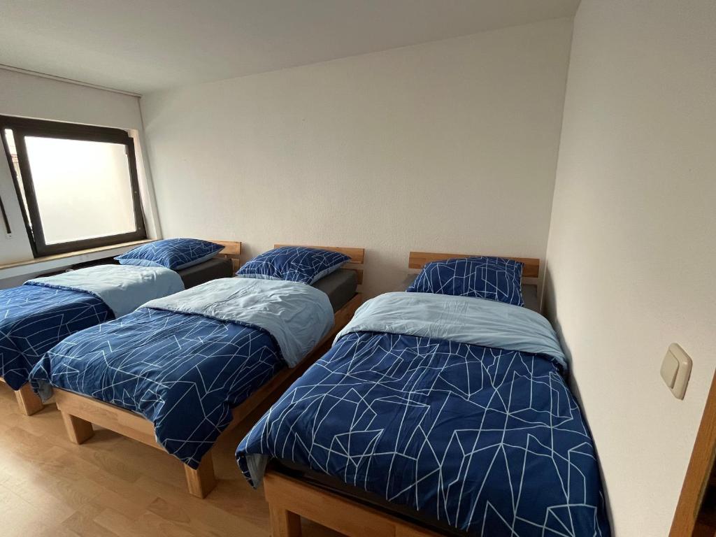 埃森Apartment Essen的一间卧室设有三张床、蓝色棉被和窗户