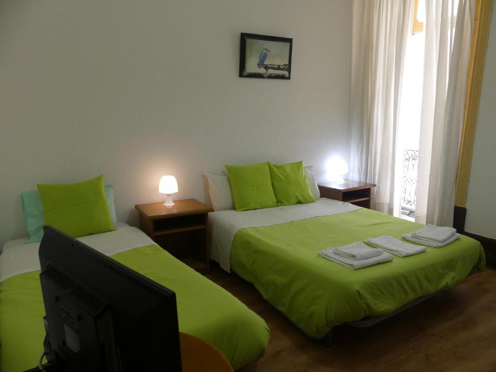 科英布拉Pensão Santa Cruz的一间卧室配有两张带绿色床单的床和电视。