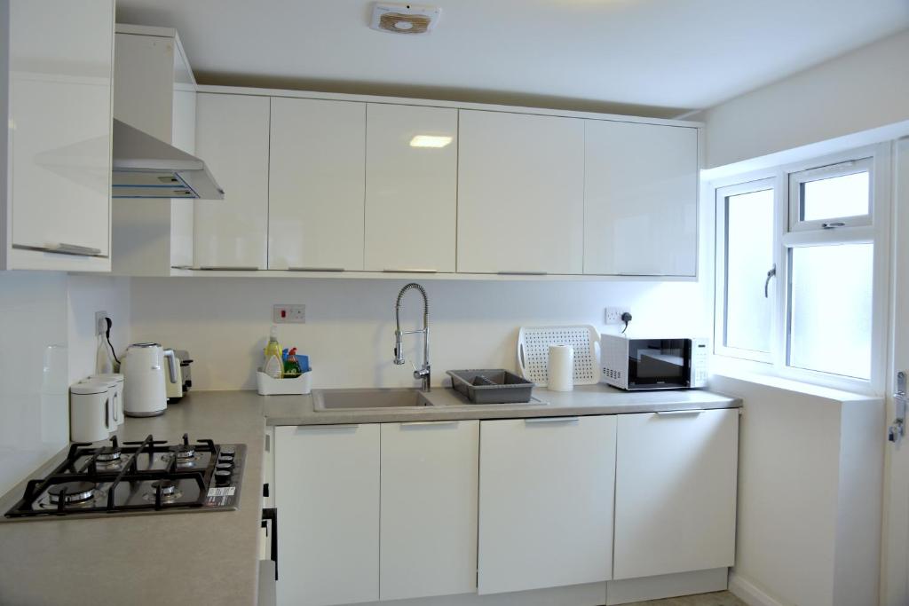 莱斯特Lindrick Villa- 3BD Bunglow , Free parking- Long stays的白色的厨房配有白色橱柜和水槽