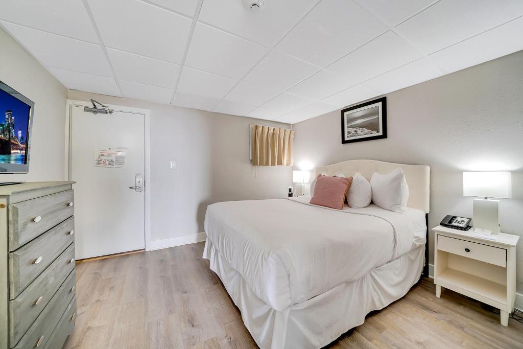 五月岬郡蒙特利尔海滩度假酒店的卧室配有白色大床和梳妆台